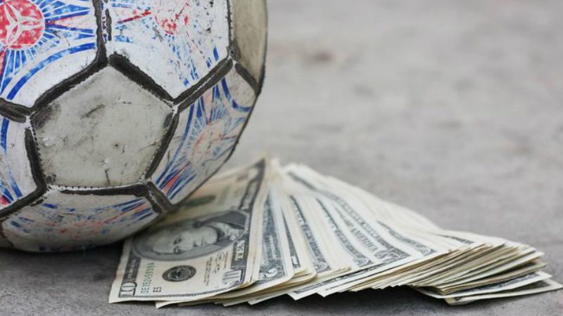 Ilustrasi Sepakbola dan Uang. Copyright: © sportskeeda