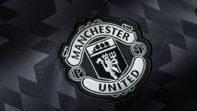 Logo Manchester United dengan background jersey tandang mereka musim depan. Copyright: © manunited.com
