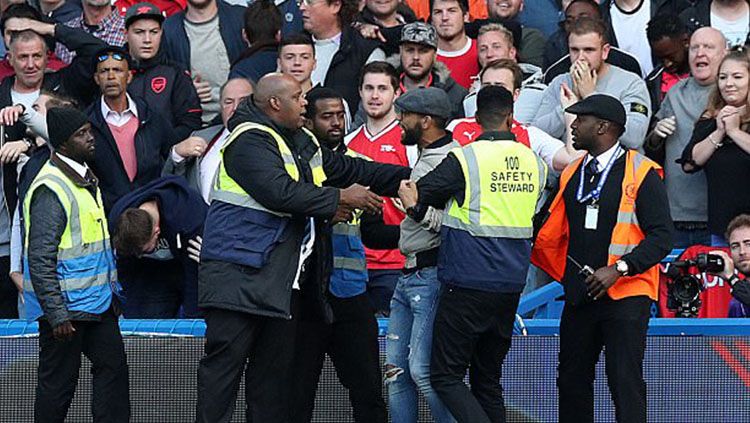 Petugas keamanan Stamford Bridge mengamankan satu fans Arsenal yang nekat masuk ke dalam lapangan. Copyright: © Daily Mail