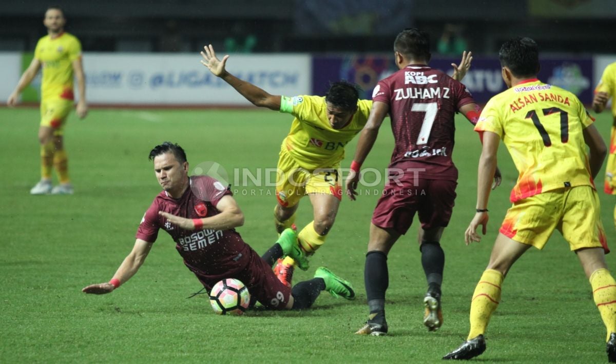 Striker PSM Makassar, Pavel Puriskhin (kiri) dijatuhkan pemain BFC. Copyright: © Herry Ibrahim/INDOSPORT