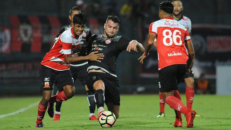 Striker Persija, Marko Simic, di tengah penjagaan pemain Madura United. Copyright: © Persija