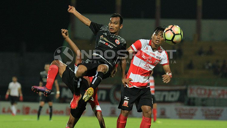 Riko Simanjuntak dibuat terbang untuk menghindari kawalan ketat pemain Madura United. Copyright: © Ian Setiawan/INDOSPORT