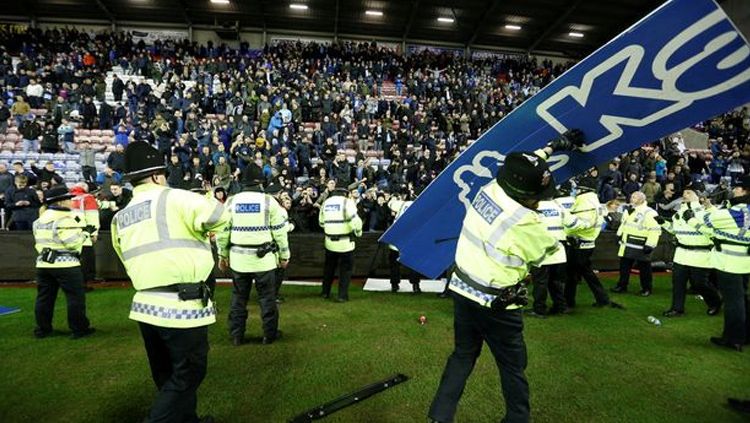 Suporter Wigan Athletic melemparkan papan iklan ke arah polisi atau ke dalam lapangan. Copyright: © Getty Images