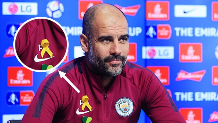 Pep Guardiola saat bertemu dengan awak media dengan memakai pita kuning di bagian dada. Copyright: © Getty Images