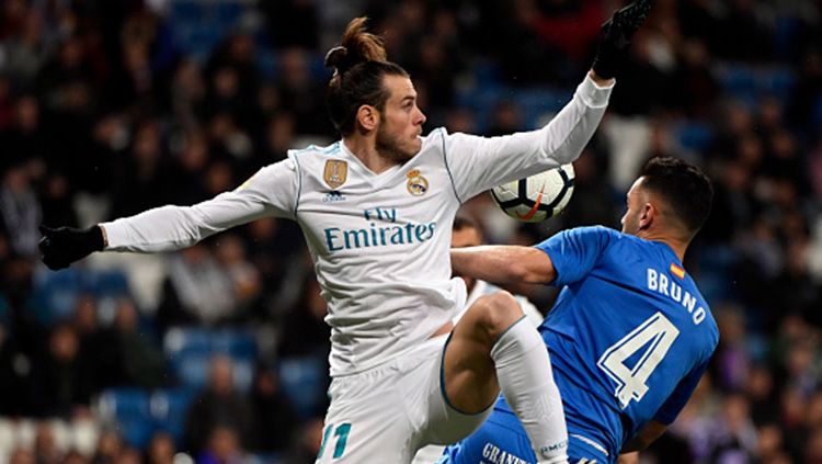 Gareth Bale (kiri) berduel di udara dengan pemain Getafe. Copyright: © Getty Images