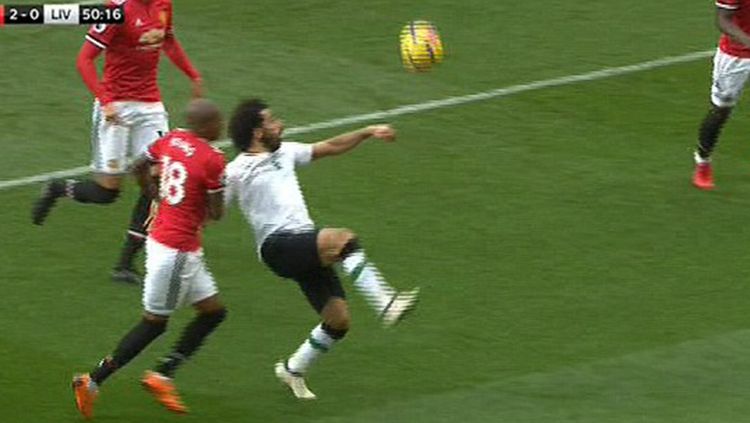 Ashley Young mencoba menjatuhkan Mohamed Salah di area kotak penalti Man United. Copyright: © Daily Mail