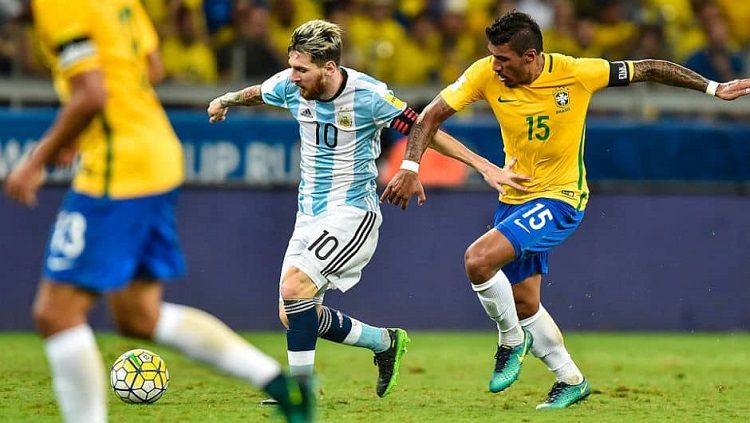 Paulinho (kanan) coba merebut bola dari Lionel Messi. Copyright: © Vivaronews.com