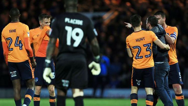 Pemain Oldham Athletic AFC menhentikan penyusup lapangan yang hendak menyerang wasit. Copyright: © Manchester Evening News