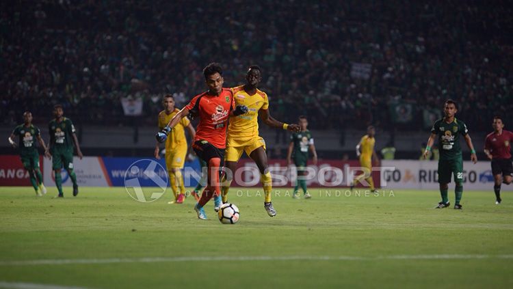 Perebutan bola antara Makan Konate dengan penjaga gawang Persebaya Copyright: © INDOSPORT/Muhammad Effendi