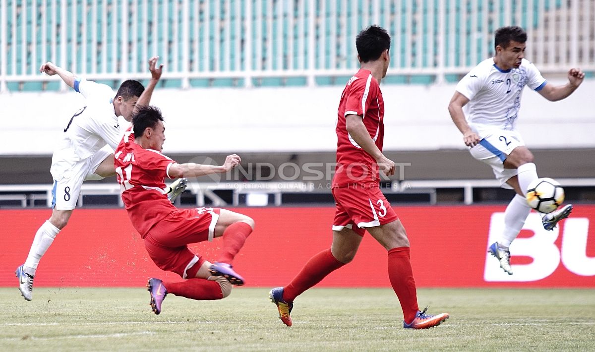 Pemain Uzbekitan, Kenjabev Islom (kiri) melepaskan tendangan ke gawang Korut. Copyright: © Herry Ibrahim/INDOSPORT