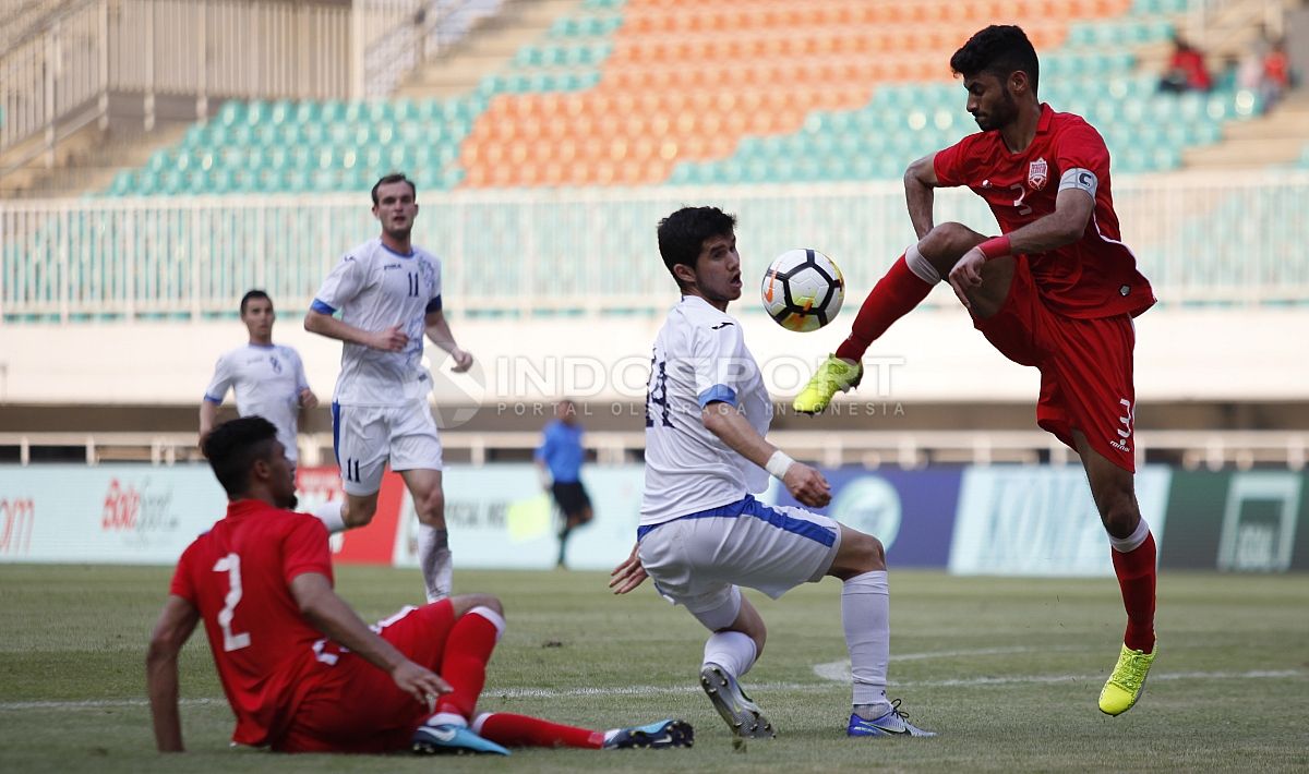 Pemain Bahrain (bawah) mencoba menghalangi pergerakan pemain Uzbekistan, Nurulloev Sukhrob. Herry Ibrahim Copyright: © Herry Ibrahim/INDOSPORT