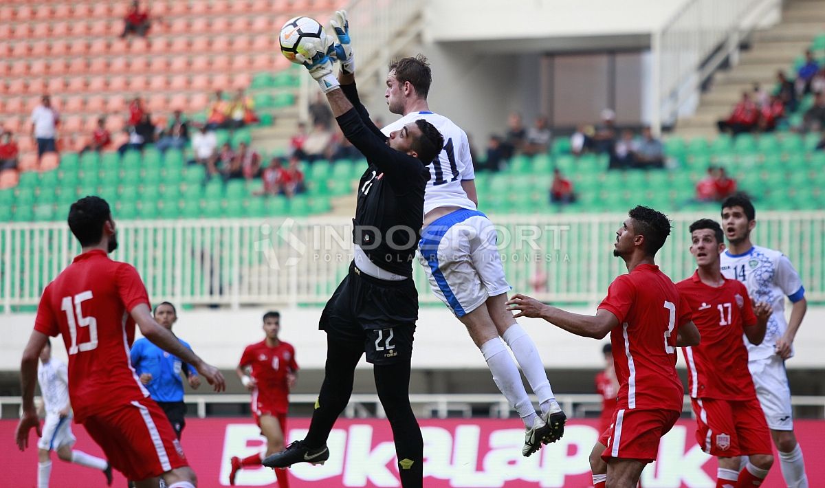 Kiper Bahrain, Sayed Mohamed Shubbar menangkap bola yang mengarah ke striker Uzbekistan, Sidorov Andrey. Copyright: © Herry Ibrahim/INDOSPORT