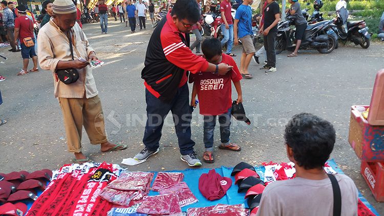 Pedagan atribut PSM Makassar, Hamdjah (kaos abu-abu) di sekitaran Stadion Andi Mattalatta Mattoangin. Copyright: © Wira Wahyu Utama/INDOSPORT