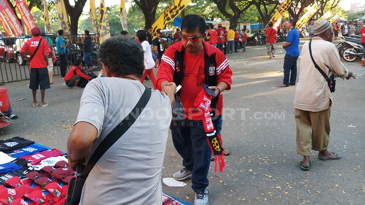 Pedagan atribut PSM Makassar, Hamdjah (kaos abu-abu) di sekitaran Stadion Andi Mattalatta Mattoangin. Copyright: © Wira Wahyu Utama/INDOSPORT