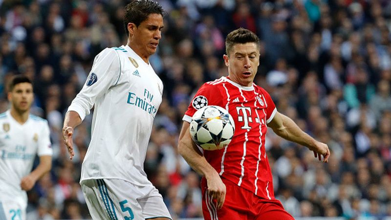 Robert Lewandowski (kanan) bersaing dengan Raphael Varane. Copyright: © Getty Images