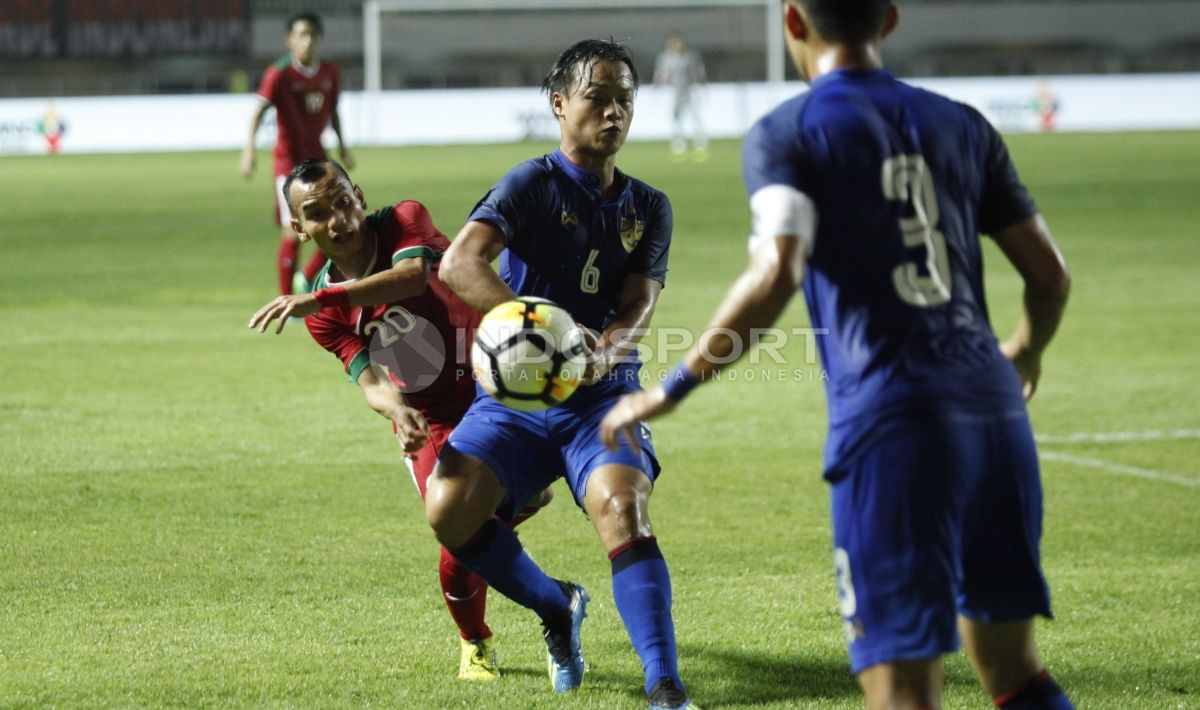 Perebutan bola antara Riko Simanjuntak dengan pemain bertahan Thailand U-23. Copyright: © INDOSPORT/Herry Ibrahim