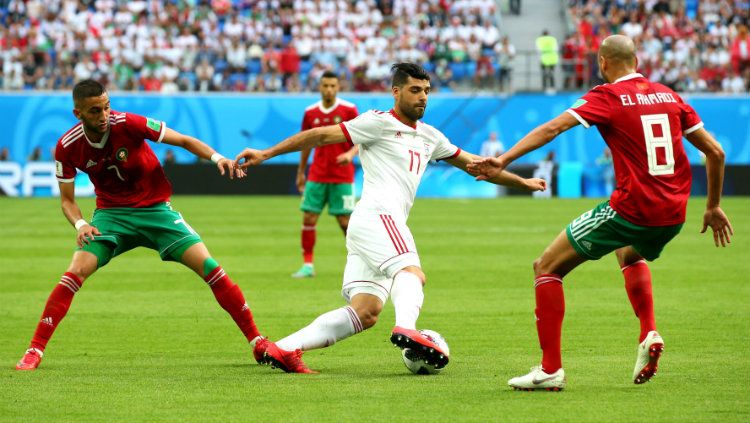 Mehdi Taremi dijegal Hakim Ziyach (kiri) dan Karim El Ahmadi (kanan) di laga Piala Dunia 2018 antara Iran dan Maroko. Copyright: © Getty Images