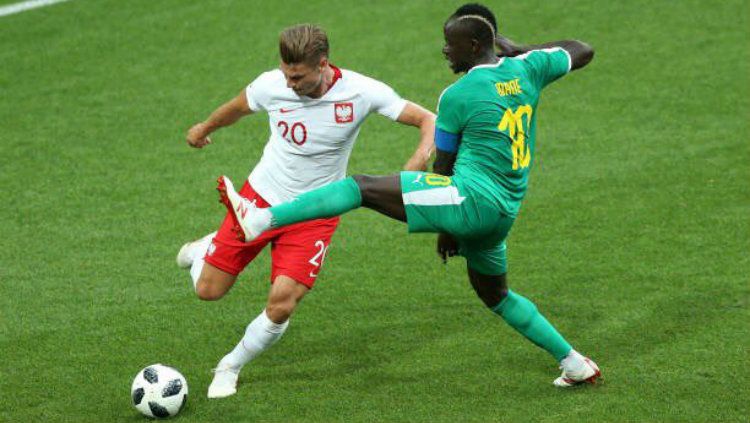 Bek Polandia Lukasz Piszczek berusaha membuang bola dan dihalau pemain Senegal Sadio Mane di Piala Dunia 2018. Copyright: © Getty Images