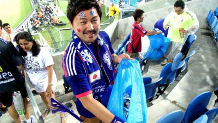 Para suporter Jepang membersihkan sampah yang ada di tribune penonton pasca pertandingan Kolombia vs Jepang di Piala Dunia 2018. Copyright: © Getty Images