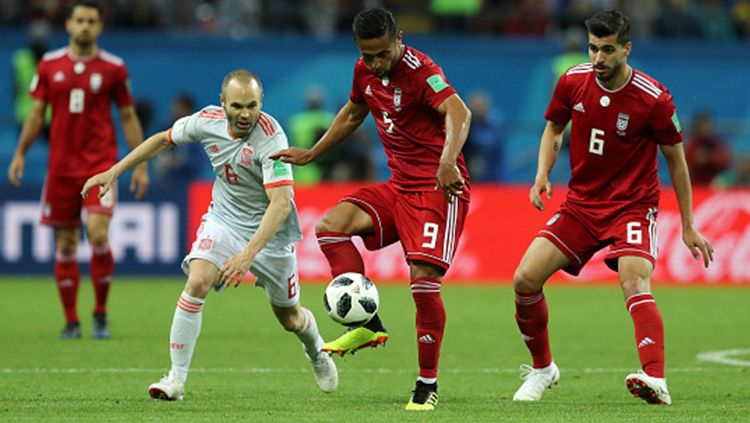 Pemain Iran mendapat bola namun berusaha direbut Iniesta. Copyright: © Getty Images