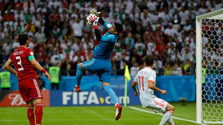 Kiper Iran, Alireza Beiranvand berusaha mengamankan gawang dari serangan pemain Spanyol di Piala Dunia 2018. Copyright: © Getty Images