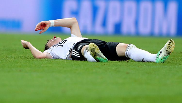 Sebastian Rudy tergeletak di lapangan setelah hidungnya patah dan berdarah. Copyright: © Simon Hofmann - FIFA via Getty Images