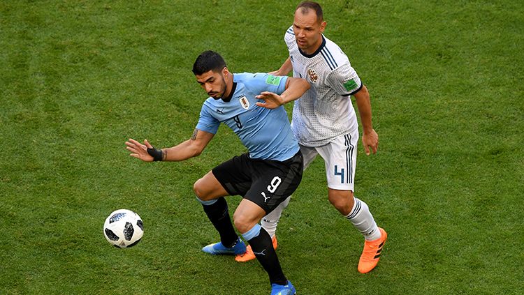 Luis Suarez menjaga penguasaan bola di tengah bayang-bayang pemain Rusia. Copyright: © Getty Images