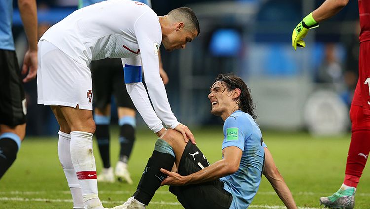 Cristiano Ronaldo bersama Edinson Cavani yang tergeletak karena cedera. Copyright: © Getty Images