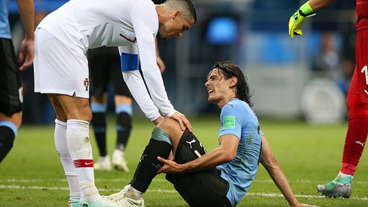 Striker Timnas Portugal, Cristiano Ronaldo (kiri) turut membantu Edinson Cavani yang tengah kesakitan. Copyright: © Getty Images