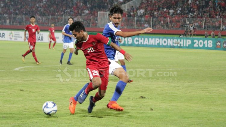 Asnawi Mangkualam duel dengan pemain Singapura U-19 untuk mendapatkan bola. Copyright: © Fitra Herdian/Indosport