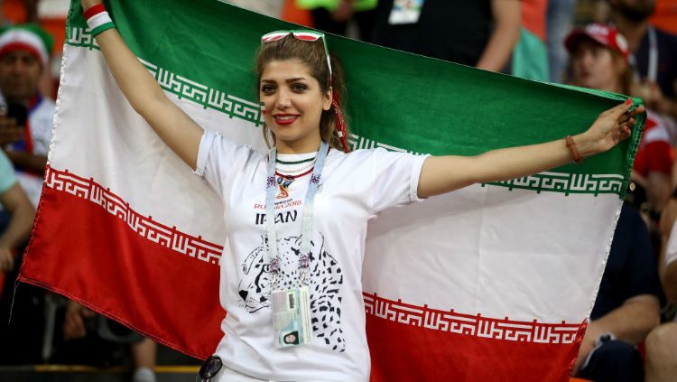 Fans wanita Iran sedang mengibarkan bendera negara asalnya. Copyright: © Getty Images