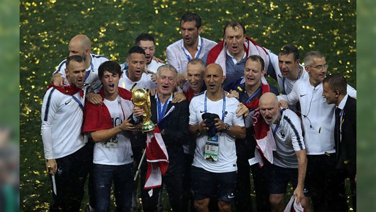Ekspresi kegembiraan Didier Deschamps dan staf pelatih Timnas Prancis sambil memegang trofi Piala Dunia. Copyright: © Getty Images