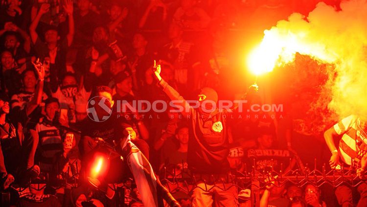 Oknum suporter sepak bola menyalakan flare saat pertandingan berlangsung. Copyright: © Fitra Herdian/INDOSPORT