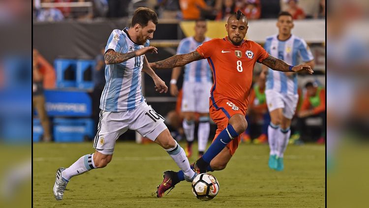 Lionel Messi (kiri/Argentina) dan Arturo Vidal (Chile) saat berduel dalam laga internasional. Copyright: &copy; Getty Images
