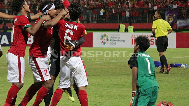 Teks foto Pemandangan kontras kiper Thailand U-16 Anuchid Taweesri meratapi kegagalannya. Pemain Indonesia U-16 merayakan kemenangan. Copyright: © Fitra Herdian/INDOSPORT