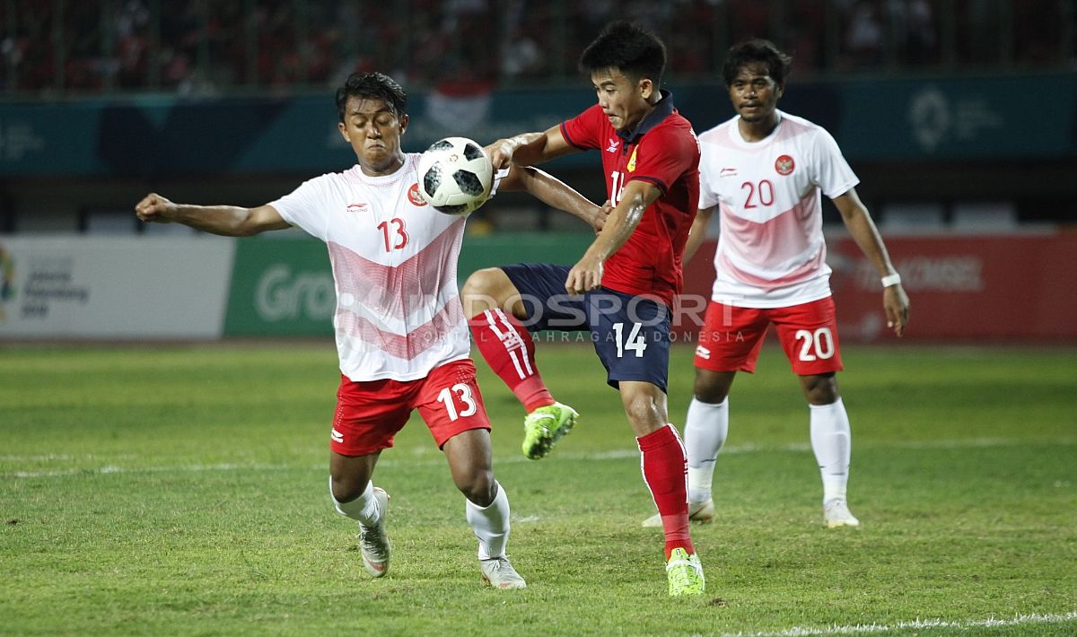 Febri Hariyadi berusaha merebut bola dari kaki pemain Laos. Copyright: © INDOSPORT/Herry Ibrahim