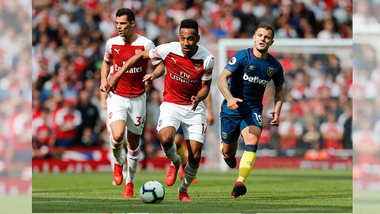 Aubameyang membawa bola sembari dibayangi Wilshere. Copyright: © Getty Images