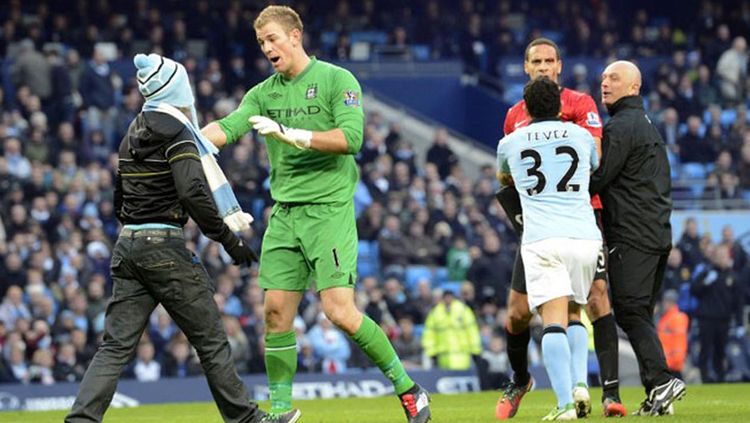 Joe Hart tengah menanggapi salah satu fans Manchester City yang masuk stadion. Copyright: © Getty Images