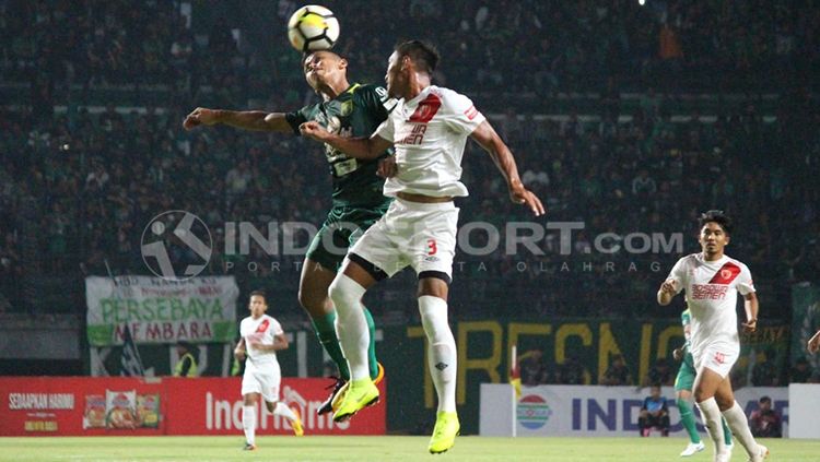 Pemain sepak bola PSM dan Persebaya tengah berduel di udara. Copyright: © INDOSPORT/Fitra Herdian