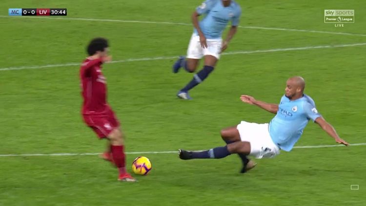 Vincent Kompany melancarkan tekel ke arah Moohamed Salah. Copyright: © Twitter.com