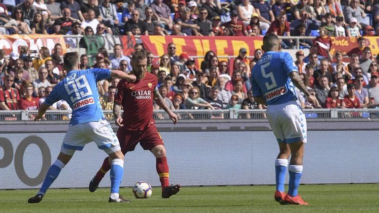 Danielle De Rossi membawa bola di antara pemain Napoli. Copyright: © @OfficialASRoma