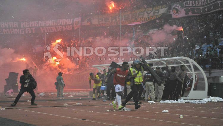 Ricky Kayame berlindung dari lemparan botol Bonek usai laga Persebaya vs Arema FC berakhir, Selasa (06/04/19). Copyright: © Fitra Herdian/INDOSPORT