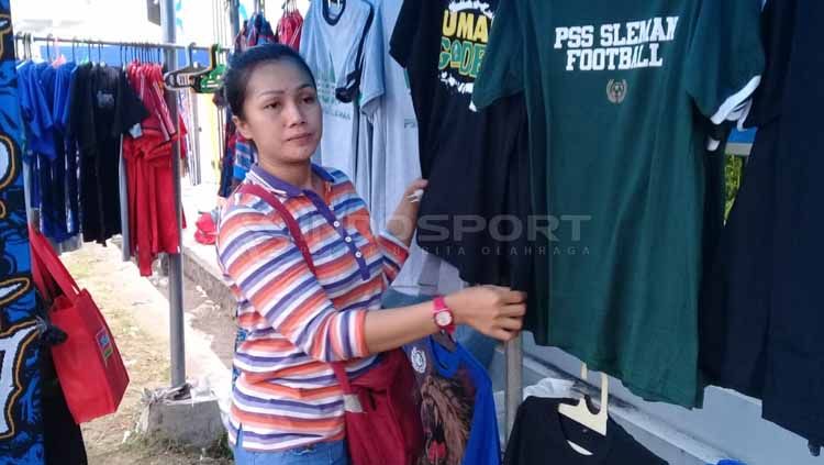Ibu Ana (40) penjual jersey dan syal asal Surabaya yang selalu berpindah-pindah stadion untuk berjualan. Copyright: © Ronald Seger Prabowo/INDOSPORT
