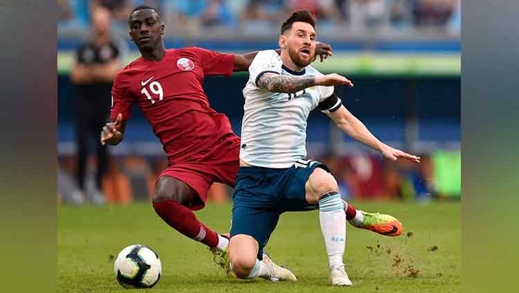 Lionel Messi gagal  membawa bola setelah mendapat jegalan dari Almoez Ali. Copyright: © Alessandra Cabral/Getty Images