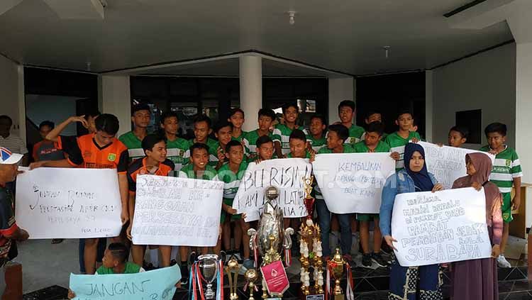 Pemain Persebaya U-14 meluapkan kekecewaan dengan membawa poster di Wisma Persebaya agar gembok segera dibuka, Senin (24-06-19). Foto: Fitra Herdian/INDOSPORT Copyright: © Fitra Herdian/INDOSPORT