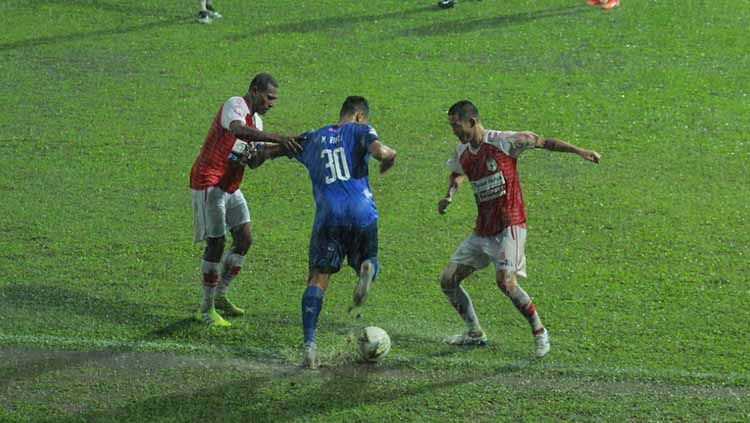 M. Rafli (tengah) lebih keras membawa bola akibat hujan deras di laga Arema FC vs Persipura Jayapura Copyright: © IAN SETIAWAN/INDOSPORT