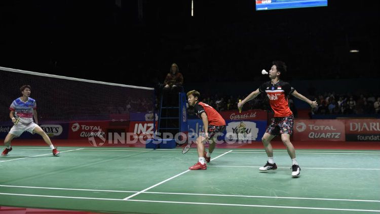 Ekspresi lucu Kevin Sanjaya dalam upaya mengembalikan kok dari serangan Li Junhui/Liu Yuchen. Copyright: © Herry Ibrahim/INDOSPORT