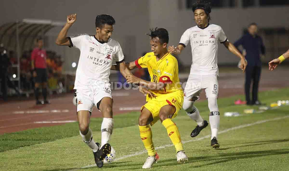 Dua pemain Madura United kawal ketat pergerakan pemain Bhayangkara FC di Liga 1 di Stadion Madya Senayan, Senin (05/08/19). Copyright: © Herry Ibrahim/INDOSPORT