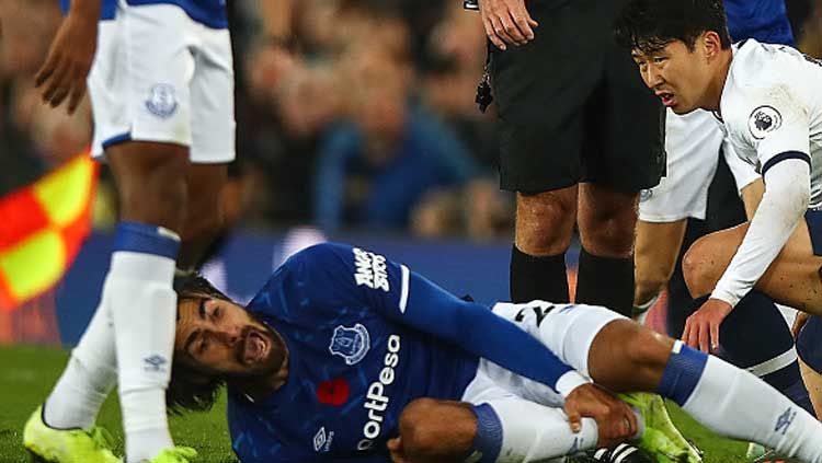 Gelandang serang Everton, Andre Gomes meringis kesakitan saat dijegal oleh penyerang Tottenham Hotspur, Son Heung-min Copyright: © Robbie Jay Barratt/GettyImages