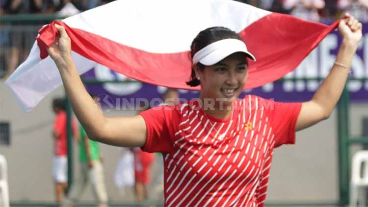 Aldila Sutjiadi mengibarkan bendera Indonesia usai meraih medali emas tenis SEA Games 2019 dari nomor tunggal putri. Copyright: © Ronald Seger Prabowo/INDOSPORT